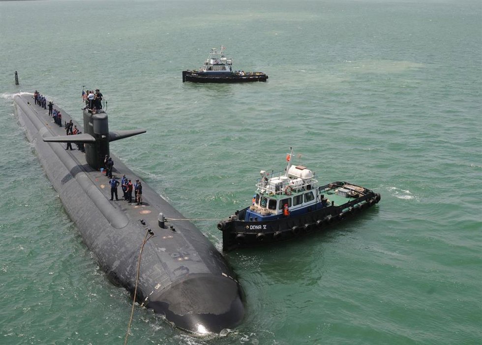 Archivo - Un remolcador guía a un submarino de EEUU en una visita al puerto de Mina Salman, en Bahréin