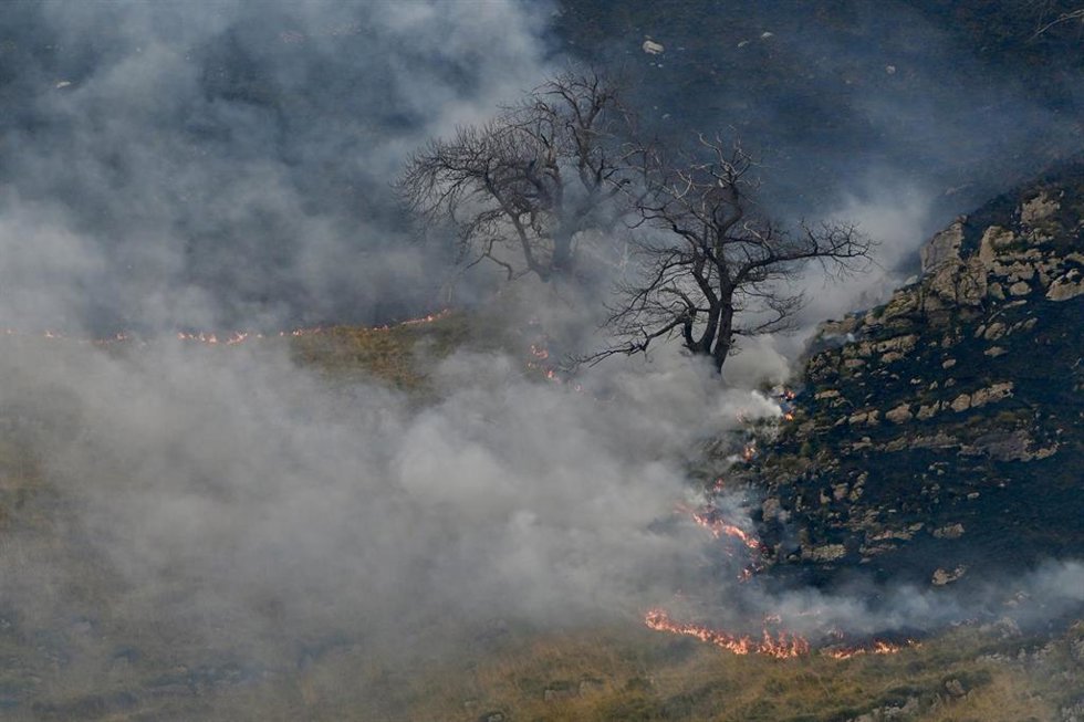Foco activo durante las labores de extinción de un incendio en Merilla en foto de achivo