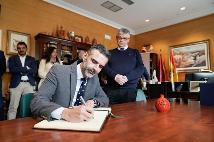 El consejero de Agricultura, Pesca, Agua y Desarrollo Rural, Ramón Fernández-Pacheco, firma en el libro de honor del Ayuntamiento de Guadix, en presencia del alcalde, Jesús Lorente