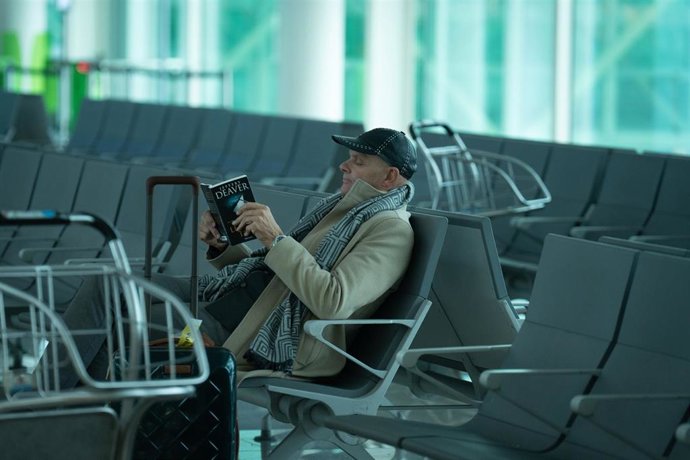Archivo - Un hombre lee sentado en el aeropuerto de El Prat.