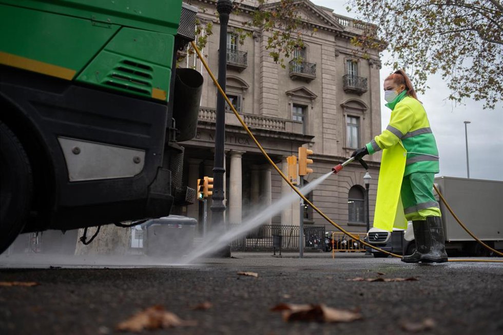 Archivo - Una trabajadora de la limpieza riega una calle con una manguera