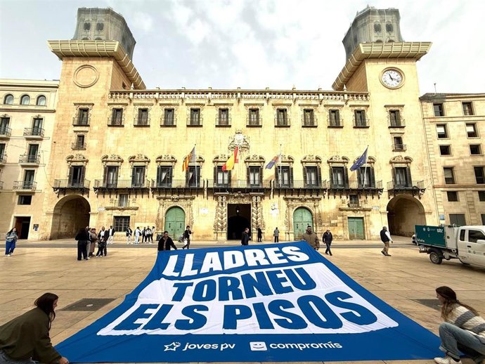 Jóvenes de Compromís exhiben una pancarta frente al Ayuntamiento de Alicante por las VPP de Les Naus