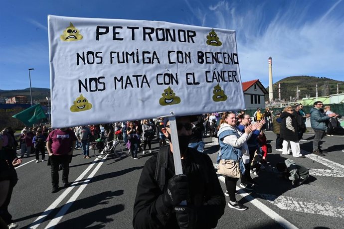 Varias personas portan pancarta con lema 'Petronor nos fumiga con beceno, nos mata con el cáncer' durante una manifestación para denunciar la fuga de benceno en una planta de Petronor, a 1 de marzo de 2026, en Abanto Zierbena y Muskiz (Bizkaia)