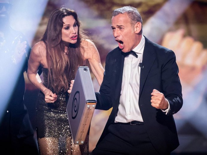 Carlos Lozano celebrando su victoria en 'GH DÚO' con el maletín del premio en la mano ante la atenta mirada de Cristina Piaget