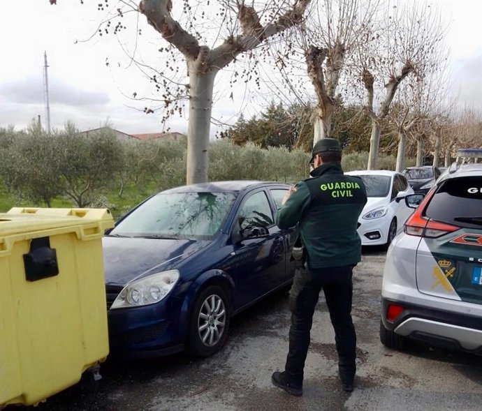 Un agente de la Guardia Civil mira uno de los vehículos afectados.
