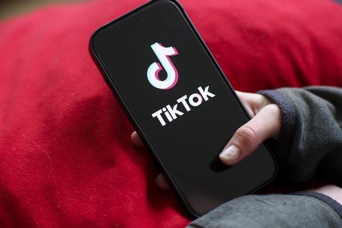 ARQUIVADO - 17 de fevereiro de 2026, Saxônia, Leipzig: Uma menina segura um iPhone 16 com o logotipo do aplicativo TikTok. O ministro da Cultura alemão, Wolfram Weimer, propôs na segunda-feira colocar a plataforma de mídia social chinesa TikTok nas mãos d