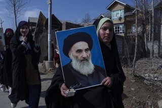 Archivo - Imagen de una adolescente con un retrato del ayatolá Alí Sistani, la máxima autoridad religiosa chií en Irak.