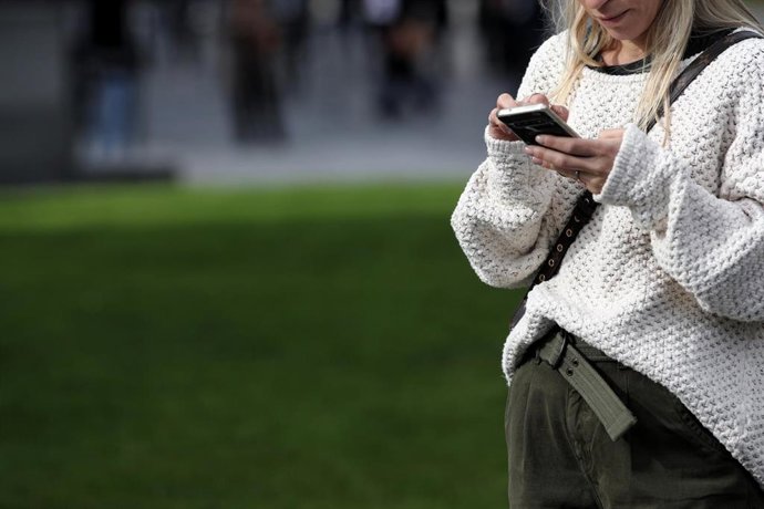Archivo - Una mujer utiliza su móvil, en Madrid a 18 de noviembre de 2019.