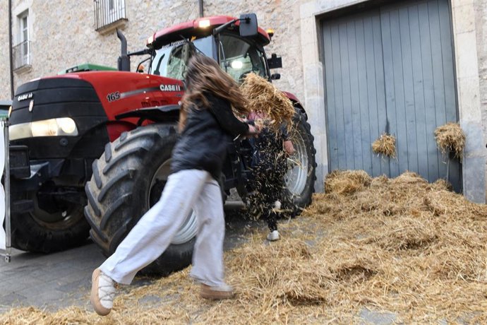 Archivo - Una mujer tira paja en la sede de la Generalitat de Catalunya en Girona durante una concentración de tractores, a 6 de febrero de 2024