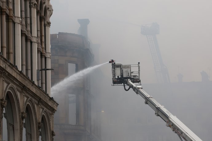 09 March 2026, United Kingdom, Glasgow: Firefighters damp down the remains of a fire that broke out in a building next to Glasgow Central railway station on Sunday. The blaze at a vape shop on Union Street leads to train cancellations.