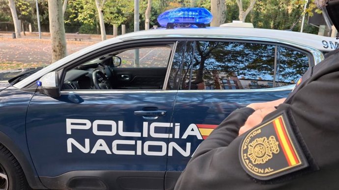 Un coche y un agente de la Policía Nacional. 