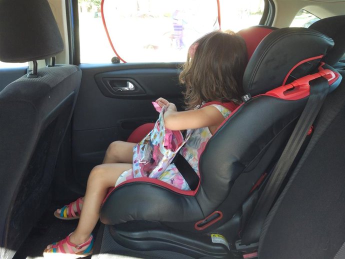 Archivo - Una menor viaja en el asiento trasero de un vehículo sentada en una silla homologada. 