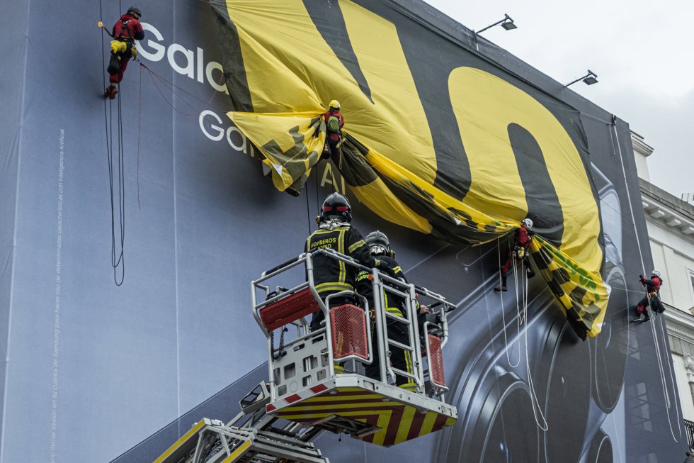 Varias personas y técnicos de los Servicios de Emergencias recogen la pancarta de Greenpeace con el mensaje No a la guerra, en la Puerta del Sol, a 10 de marzo de 2026, en Madrid (España).