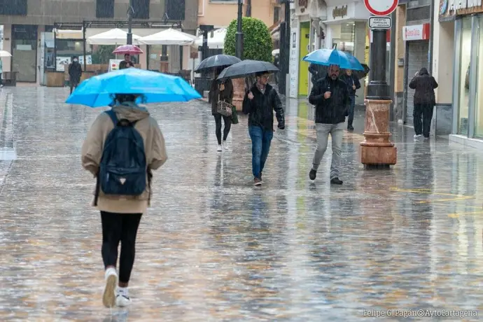 Varias personas paseando con paraguas por el centro de Cartagena bajo la lluvia en una imagen de archivo