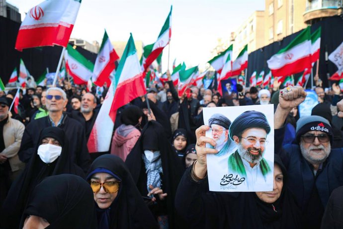 09 de março de 2026, Irã, Teerã: Manifestantes agitam bandeiras nacionais iranianas enquanto se reúnem para um comício em apoio ao novo Líder Supremo na Praça Enghelab, no centro de Teerã. O Irã comemorou a nomeação do aiatolá Mojtaba Khamenei, que sucede