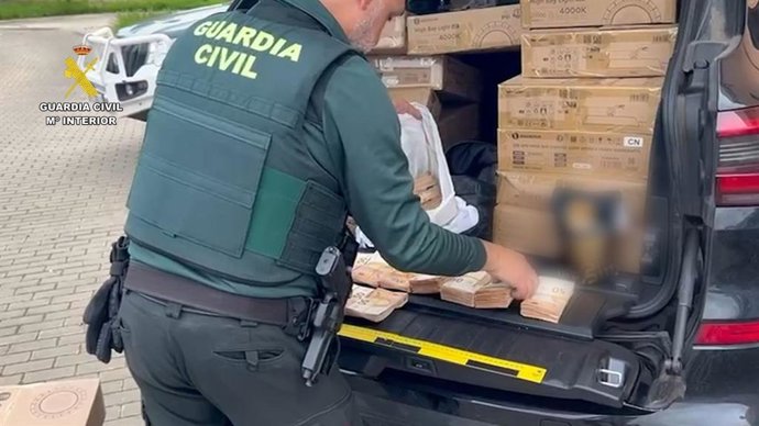 Un agente de la Guardia Civil revisa el dinero hallado oculto en un vehículo durante un control en Olvera (Cádiz)