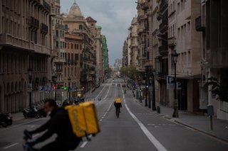 Archivo - Dos trabajadores de Glovo en bicicleta por una calle de Barcelona