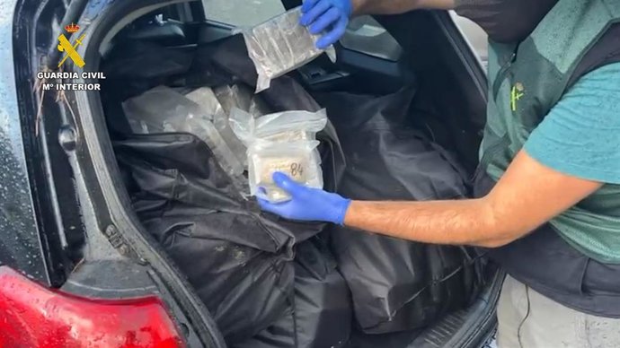 Un agente de la Guardia Civil muestra algunos de los paquetes de hachís intervenidos en el vehículo interceptado en el aparcamiento del Hospital Universitario Torrecárdenas de Almería.