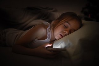 Archivo - Niña dormida con e móvil en la mano