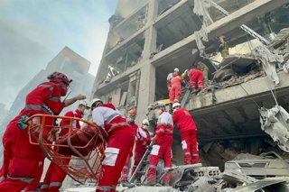 Equipos de rescate de la Media Luna Roja iraní trabajan en el lugar de un edificio dañado por un ataque aéreo en Irán
