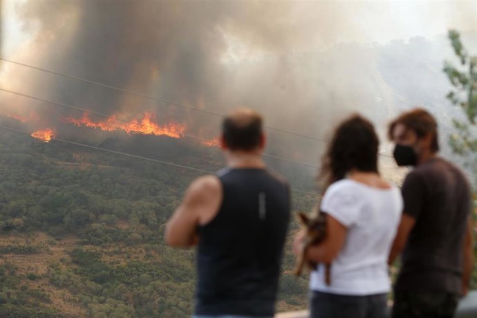 Archivo - Varias personas observan el incendio forestal  de La Baña (León) el pasado mes de agosto.