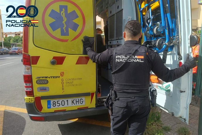 Un agente de la Policía Nacional frente a una ambulancia.