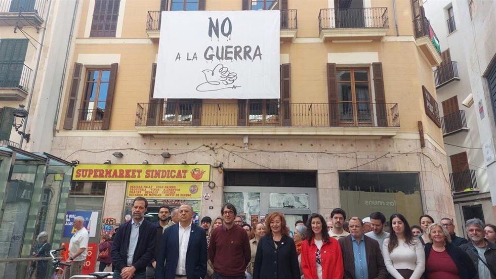 La secretaria general del PSIB, Francina Armengol, y otros representantes del PSIB ante la pancarta del 'no a la guerra' desplegada en la sede del partido en Palma.