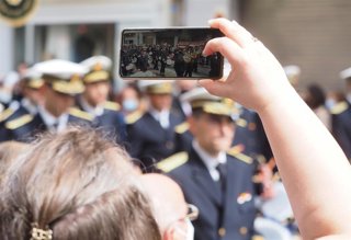Archivo - Una persona fotografía, con su teléfono móvil, una banda de música procesional en Semana Santa, en una foto de recurso.