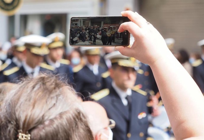 Archivo - Una persona fotografía, con su teléfono móvil, una banda de música procesional en Semana Santa, en una foto de recurso.