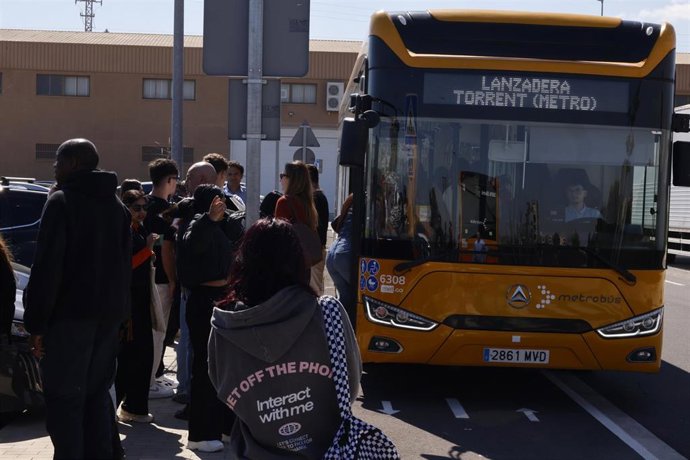 Varias personas hacen cola para coger un bus lanzadera en el exterior de la estación de cercanías de Albal, a 13 de marzo de 2026. 