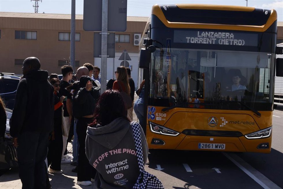 Varias personas hacen cola para coger un bus lanzadera en el exterior de la estación de cercanías de Albal, a 13 de marzo de 2026.
