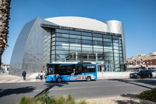 El autobús turístico eléctrico 'Roquebús' circula frente al Teatro Auditorio de Roquetas de Mar (Almería).