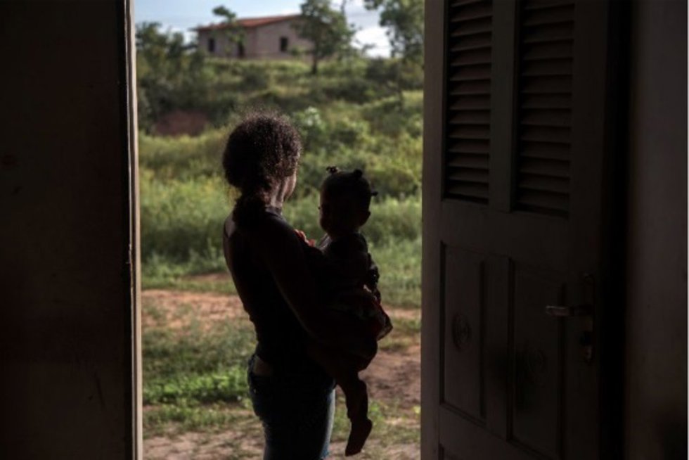 Archivo - Una madre adolescente mira al horizonte mientras sostiene en brazos a su bebé en Brasil