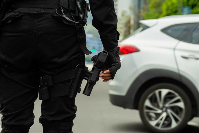 Archivo - Arquivo - 23 de dezembro de 2024, Quito, Equador: Uma policial fica de guarda com uma arma na mão durante o protesto. Após vários dias de medo, centenas de pessoas se manifestaram pacificamente em meio à angústia e à raiva causadas pela violênci