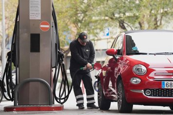 Un hombre echando combustible a su vehículo en una gasolinera