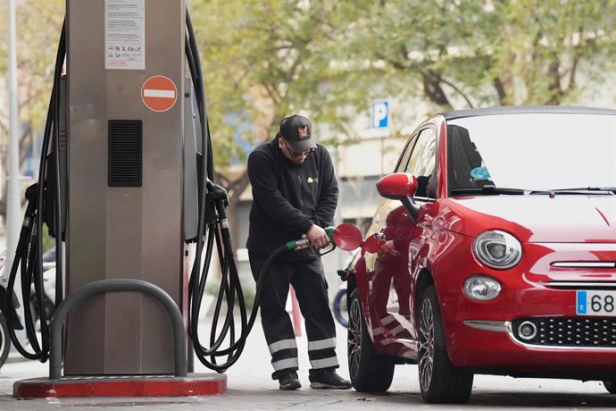Un hombre echando combustible a su vehículo en una gasolinera