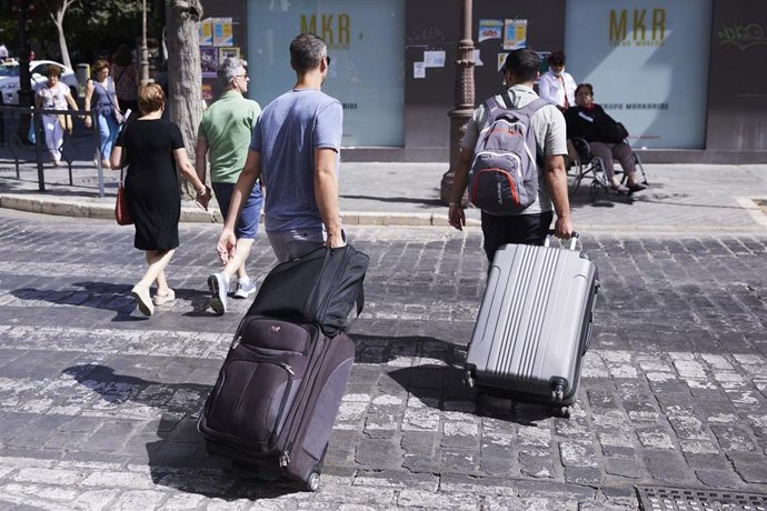 Archivo - Dos turistas, con maletas, cruzan un paso de peatones a 21 de junio de 2022 en Sevilla (Andalucía, España)