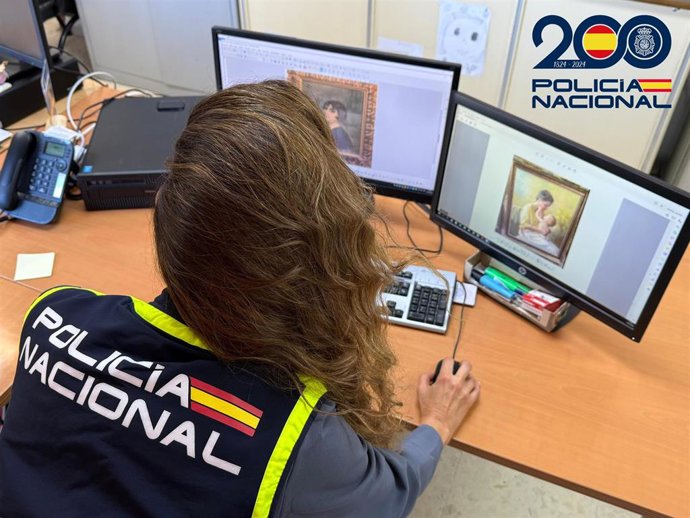 Un agente examina imágenes de algunas de las obras presuntamente apropiadas por el supuesto marchante en Almería.