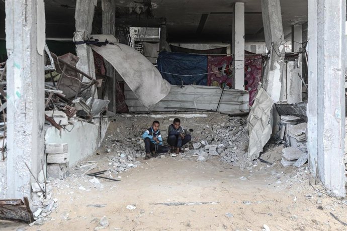 Archivo - Dos palestinos en un edificio destruido por el Ejército de Israel en el campamento de refugiados de Al Bureij, en la Franja de Gaza (archivo)