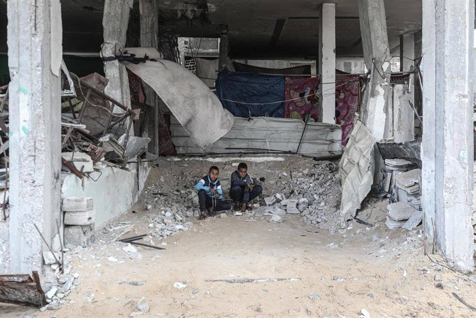 Archivo - Dos palestinos en un edificio destruido por el Ejército de Israel en el campamento de refugiados de Al Bureij, en la Franja de Gaza (archivo)