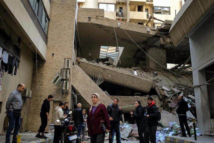 Grupo de personas ante los restos de un edificio destruido por los ataques de Israel contra la capital libanesa, Beirut