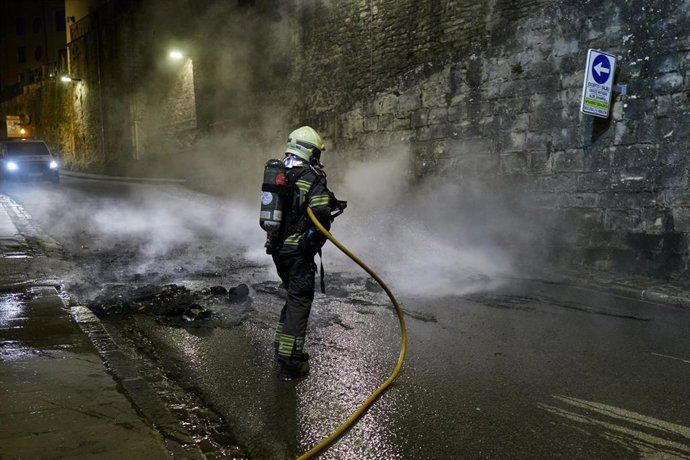 Un bombero apaga un contenedor ardiendo durante los piquetes para un SMI propio para el País Vasco y Navarra, a 17 de marzo de 2026, en Pamplona, Navarra (España). Los sindicatos nacionalistas ELA, LAB, Steilas, Etxalde e Hiru han convocado piquetes para 