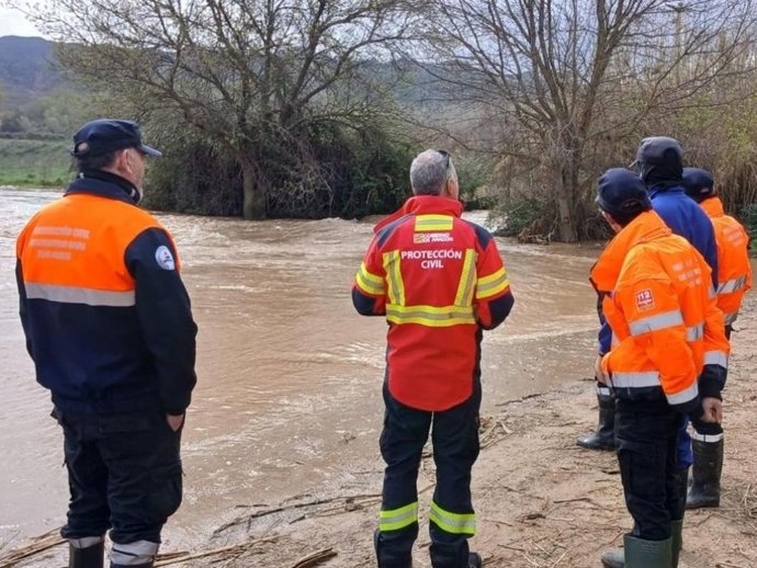 Voluntarios de Protección Civil vigilan el cauce de un río.