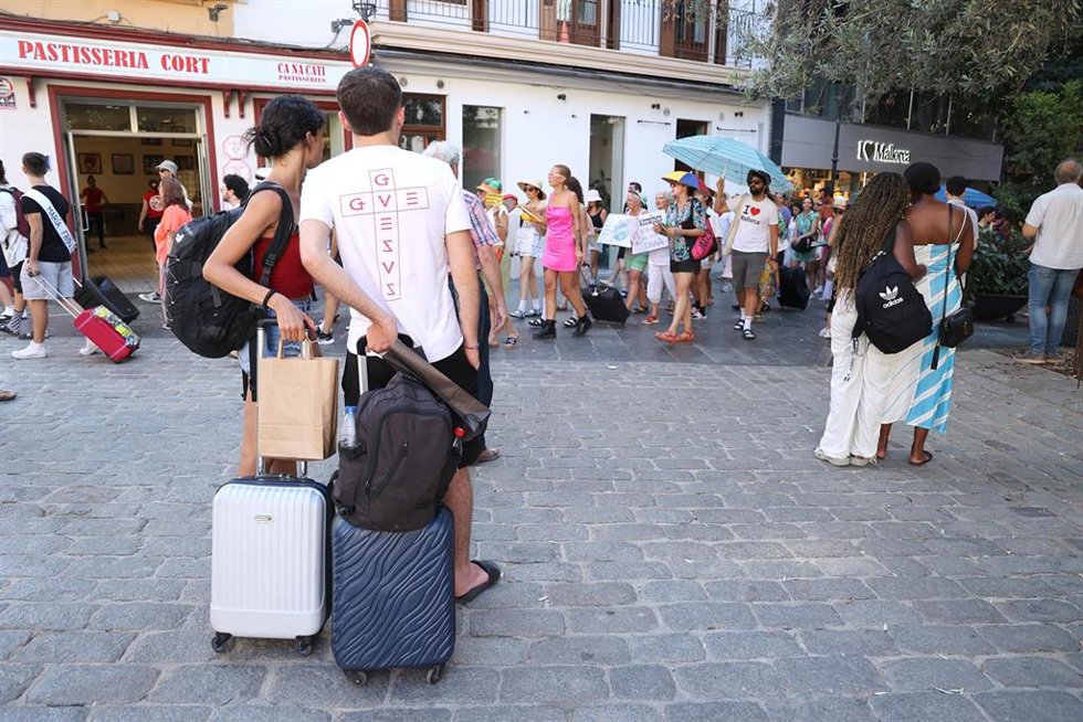 Archivo - Turistas observan una manifestación contra el turismo en la plaza de Cort.