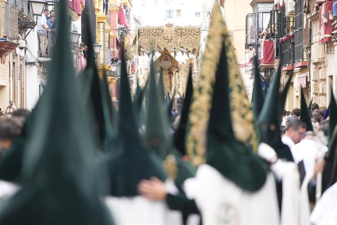 Archivo - Nazarenos de la Esperanza de Triana, con túnica y antifaz de terciopelo verde y capa blanca, en la calle Puereza, junto a la Capilla de los Marineros.