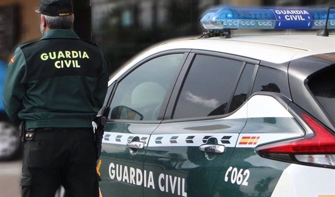 Archivo - Un agente de la Guardia Civil junto a un vehículo oficial. Imagen de archivo.