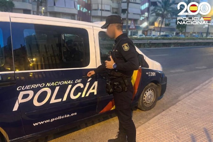 Un policía frente a un furgón de la Policía Nacional.