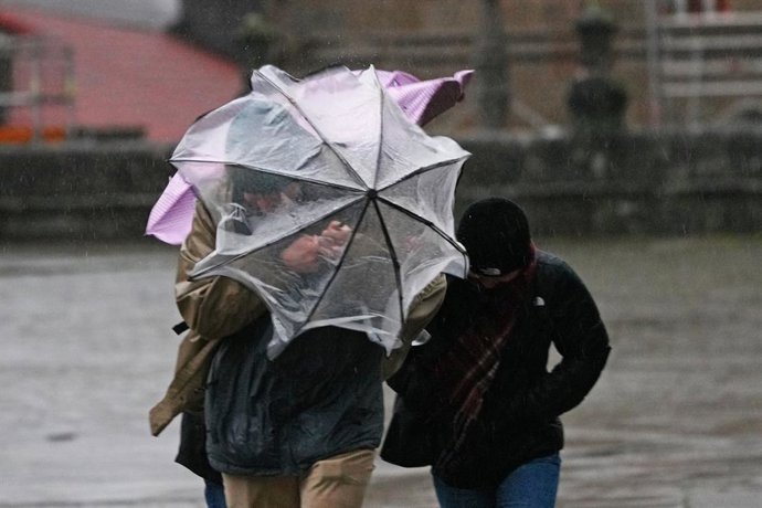 Archivo - Varias personas intentan sujetar sus paraguas, a 26 de enero de 2026, en Santiago de Compostela, A Coruña, Galicia (España). Galicia afronta este lunes una jornada de avisos por lluvias asociados a la borrasca Joseph, con distintos niveles de al