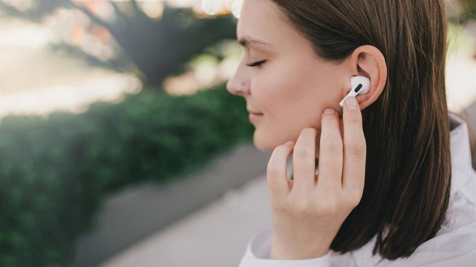 Archivo - Mujer joven usando auriculares.