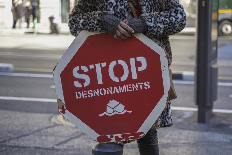 Archivo - Una persona sujeta un cartel de 'Stop desnonamients'.